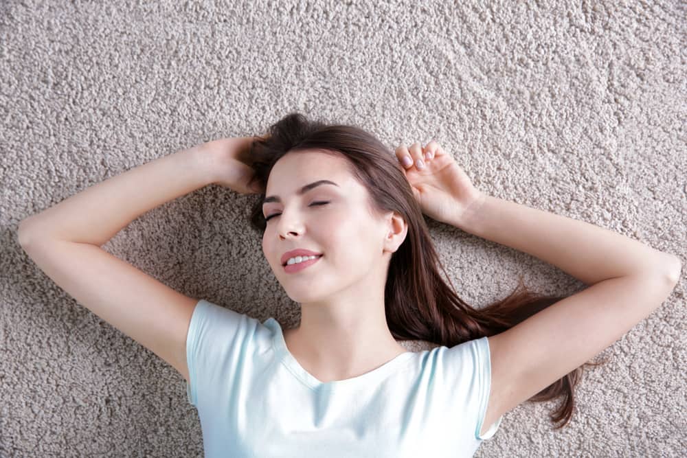 Happy young woman lying on Carpet Flooring