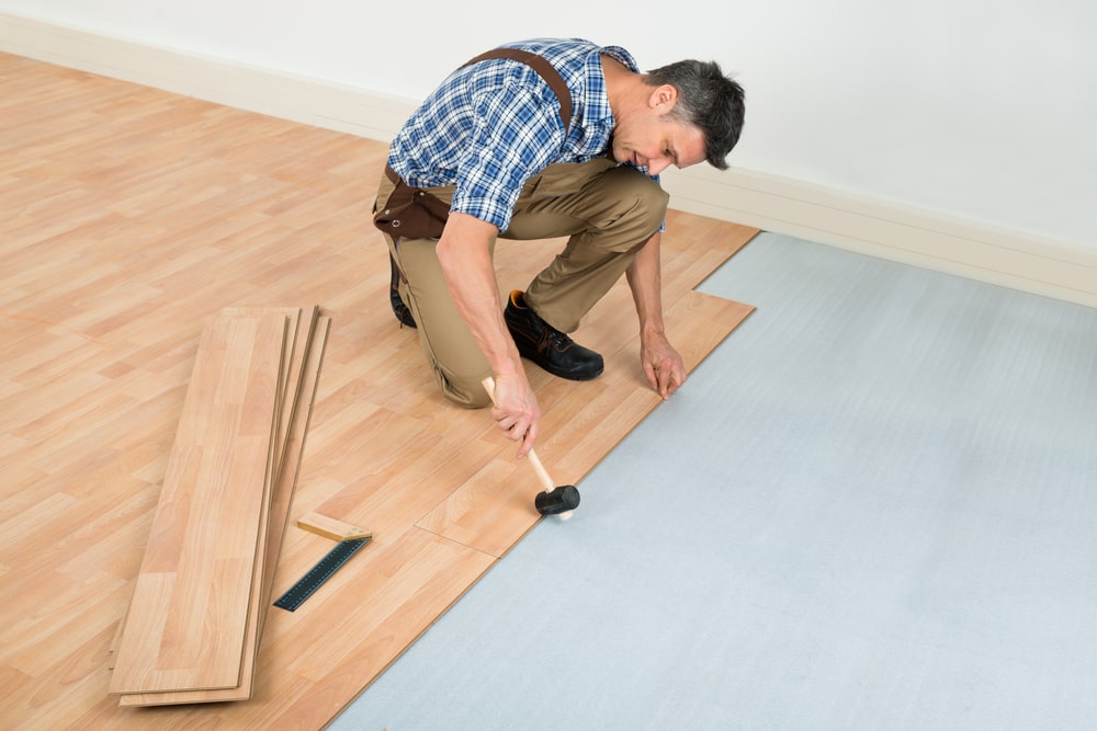 Carpenter installing new laminated wooden floor at home hardwood flooring